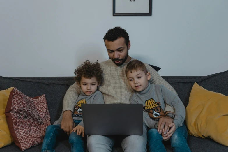 a man and two children sitting on a couch with a laptop, by Adam Marczyński, pexels contest winner, gamedev, raphael lecoste, casually dressed, ismail