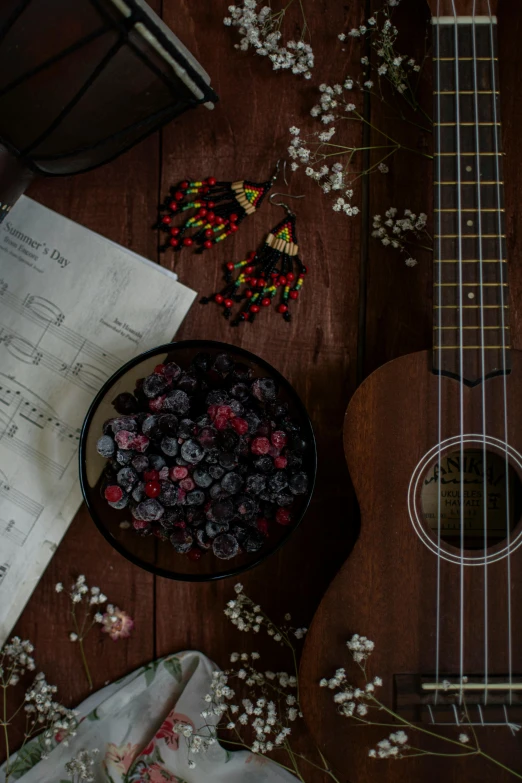 a guitar sitting on top of a wooden table, an album cover, pexels contest winner, hurufiyya, made of flowers and berries, snacks, dark hues, ukulele