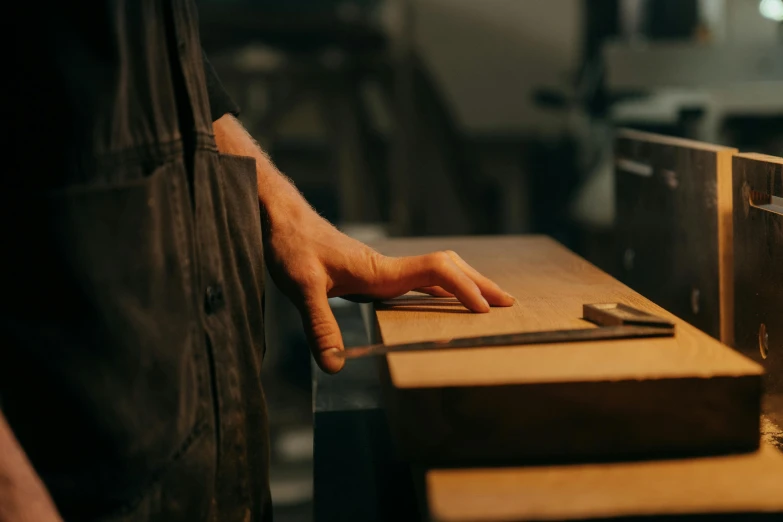 a close up of a person cutting a piece of wood, an album cover, by Tom Bonson, trending on unsplash, metalwork, lachlan bailey, ignant, small manufacture