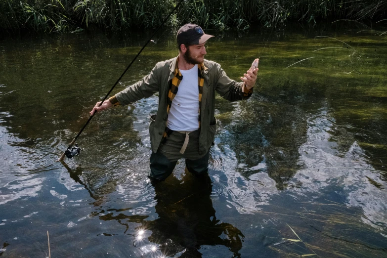 a man standing in a river holding a fishing rod, style of seb mckinnon, casually dressed, thumbnail, press shot