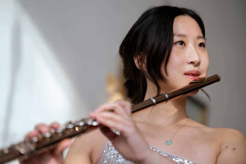 a woman in a silver dress playing a flute, an album cover, inspired by Zhou Wenjing, pexels contest winner, jaeyeon nam, performance, youtube thumbnail, portrait image