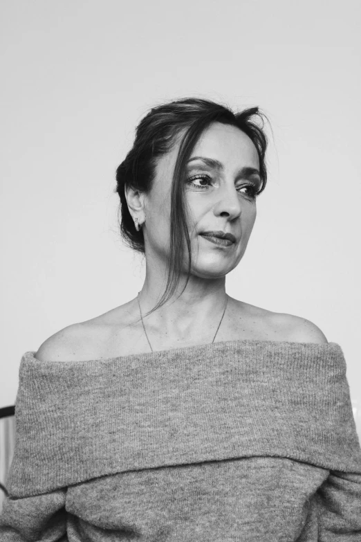 a black and white photo of a woman in a sweater, inspired by Lucia Peka, ana de la reguera portrait, ritu kumar, looking her shoulder, high view