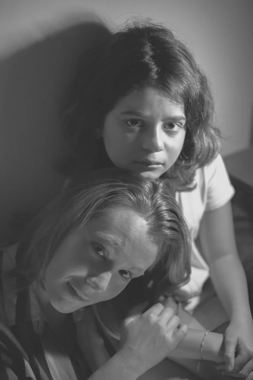 a couple of women sitting on top of a bed, a black and white photo, inspired by Roy DeCarava, renaissance, kids, promotional image, jodie foster, migrant mother