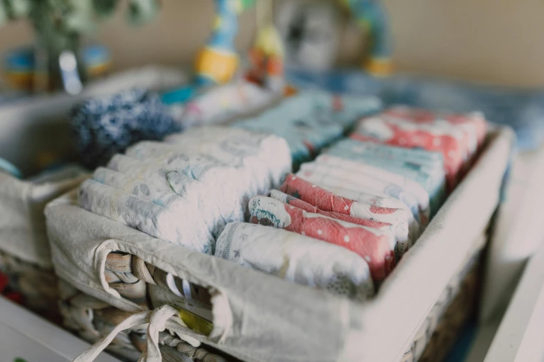 a basket filled with diapers sitting on top of a table, by Helen Stevenson, unsplash, muted blue and red tones, emma bridgewater and paperchase, close up half body shot, in a row