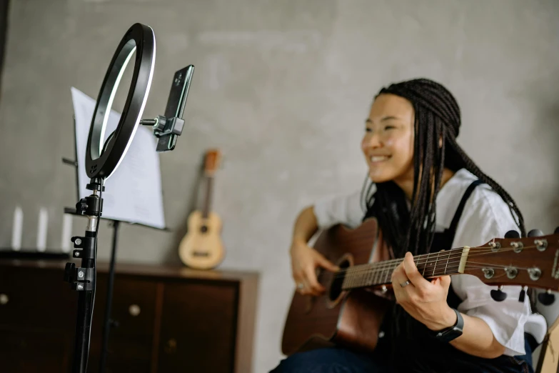 a woman playing a guitar in front of a microphone, trending on pexels, avatar image, selfie photo, asian female, thumbnail