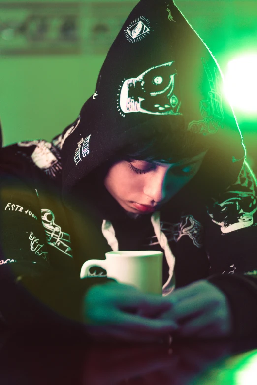 a person sitting at a table with a cup of coffee, an album cover, inspired by Elsa Bleda, unsplash, graffiti, cyberpunk anime girl in hoodie, cute emo guy, sleepy expression, poker face