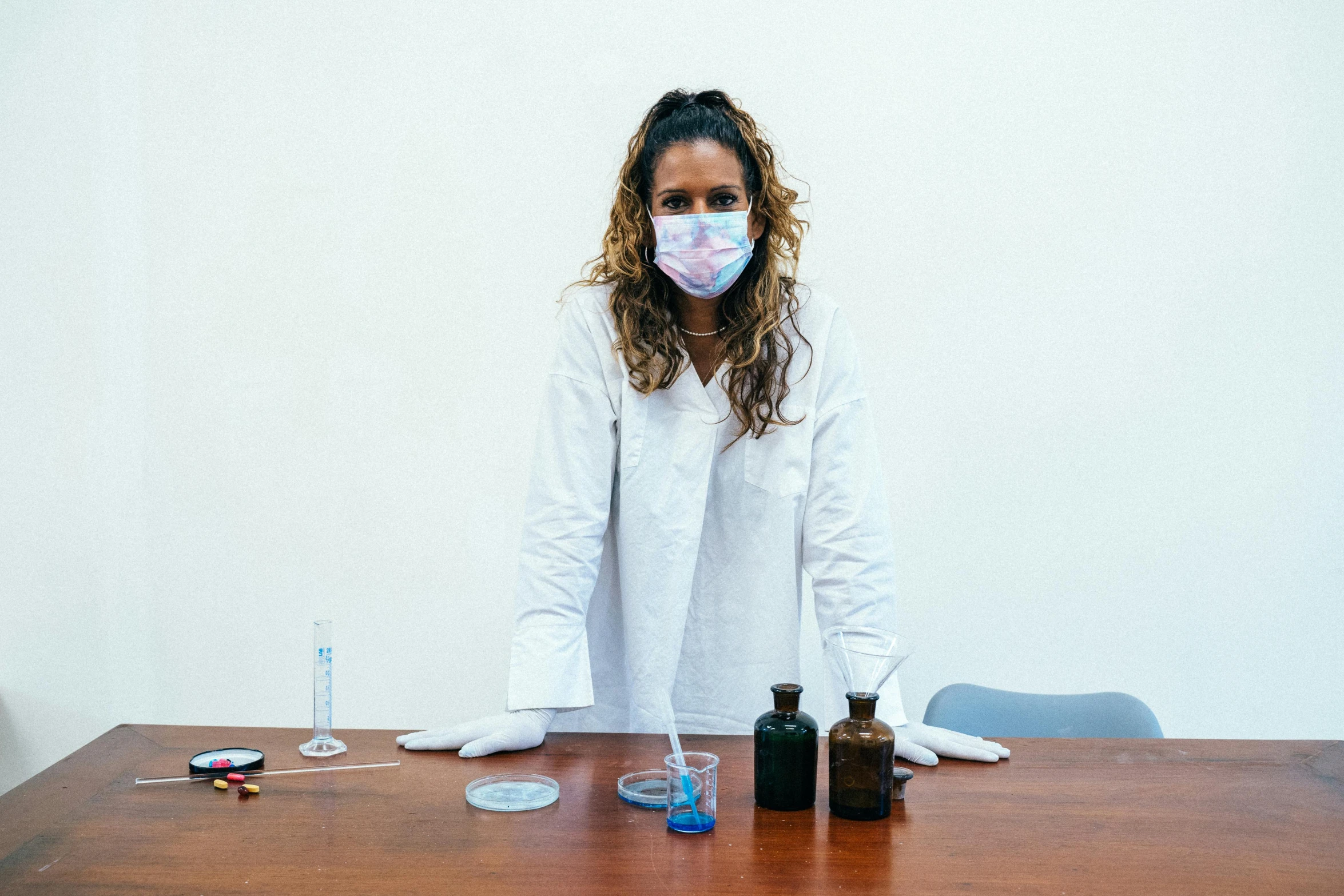 a woman wearing a face mask sitting at a table, by Olivia Peguero, experiment in laboratory, emma uber, mirka andolfo, reagents