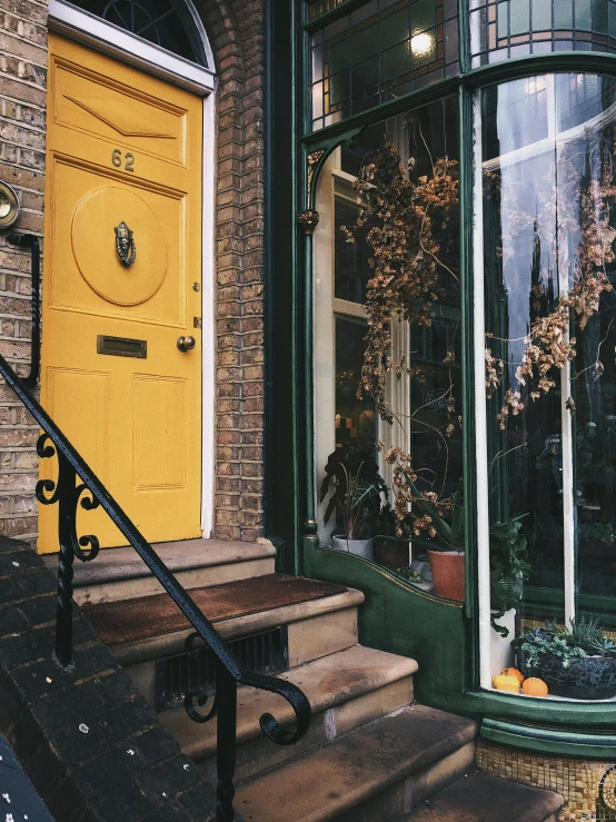 a yellow door sitting on the side of a brick building, by Nina Hamnett, pexels contest winner, arts and crafts movement, in savannah, autumnal colours, interior of a victorian house, shop front