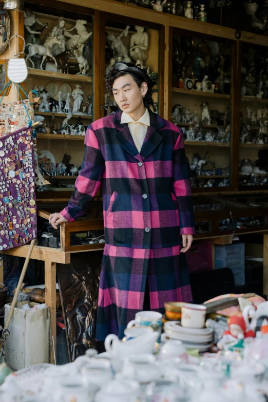 a woman standing in a room filled with lots of stuff, a portrait, inspired by Maeda Masao, unsplash, he wears a big coat, tartan garment, asian man, quirky shops