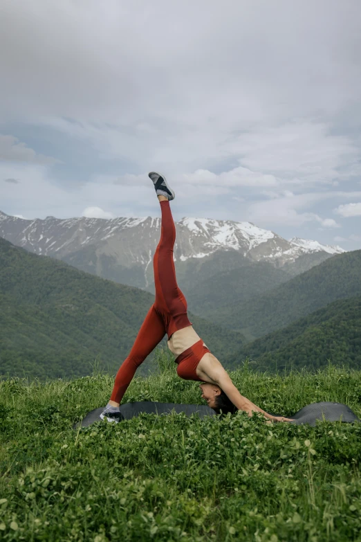 a woman doing a yoga pose in the mountains, pexels contest winner, arabesque, on a green lawn, soviet - era, leggings, turkey