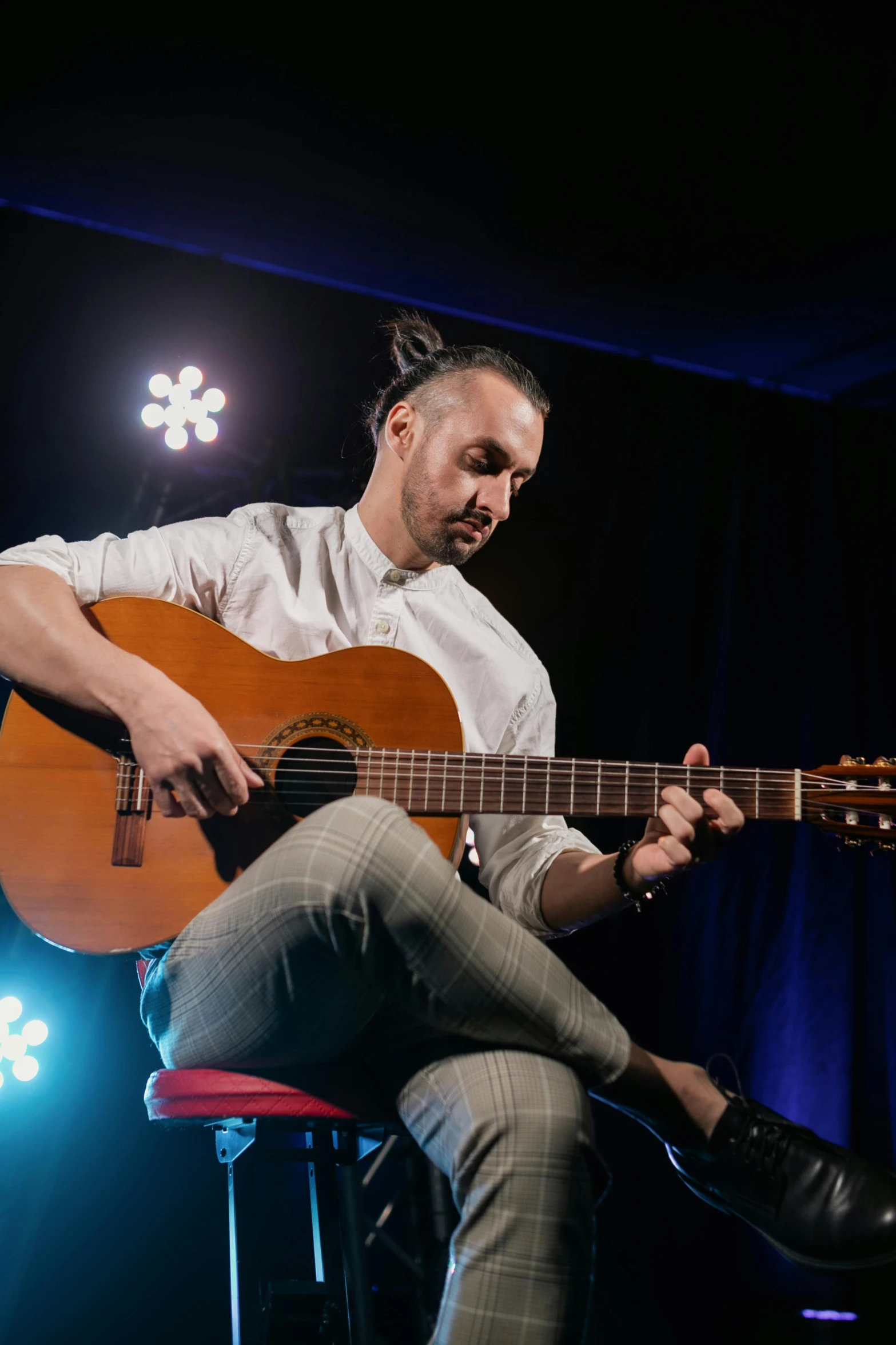 a man sitting on a stool playing a guitar, an album cover, inspired by Germán Londoño, unsplash, antipodeans, square, performance, caleb from critical role, headshot