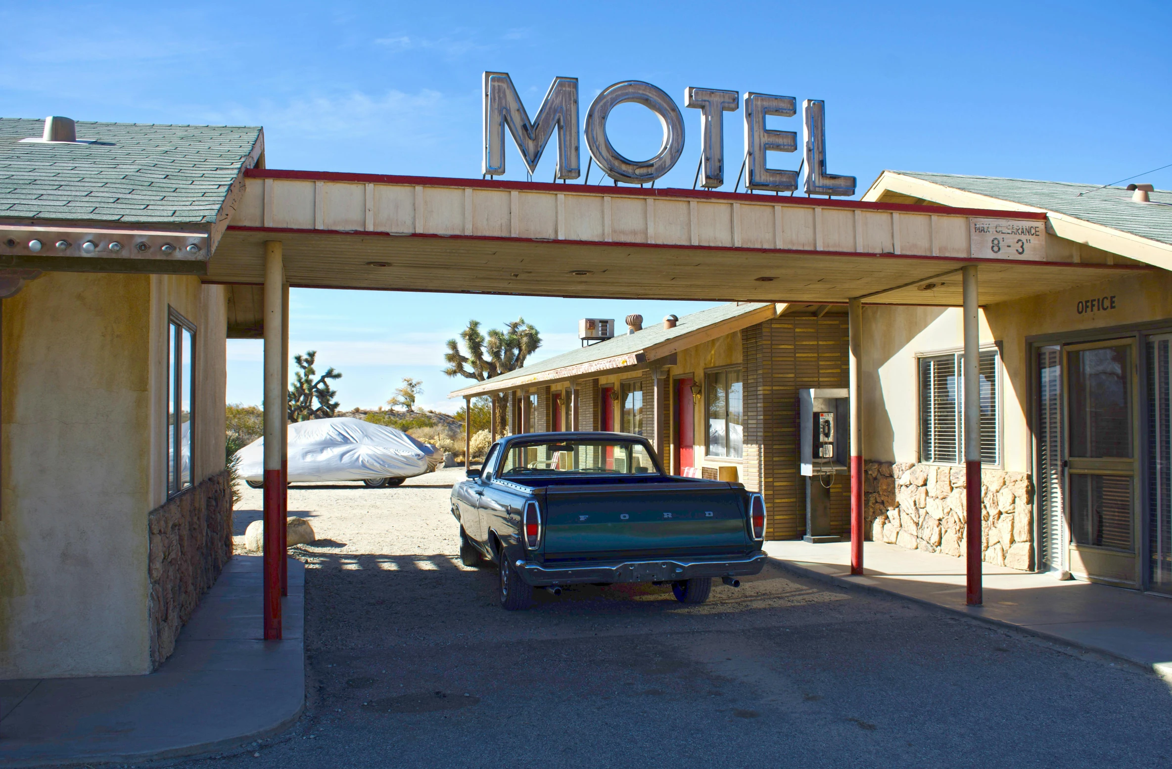 a blue truck parked in front of a motel, by Pamela Ascherson, unsplash, retrofuturism, square, road california desert, old signs, ground - level medium shot