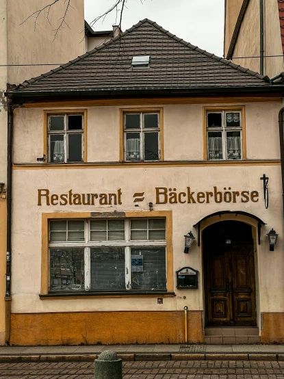 a building with a clock on the front of it, inspired by Jan Kupecký, restaurant in background, backbone, blooodborne, sign