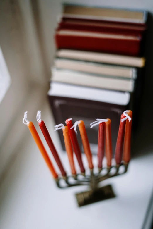 a bunch of candles sitting on top of a window sill, by Jakob Emanuel Handmann, pexels, books on side table, orange ribbons, holy ceremony, crimson themed