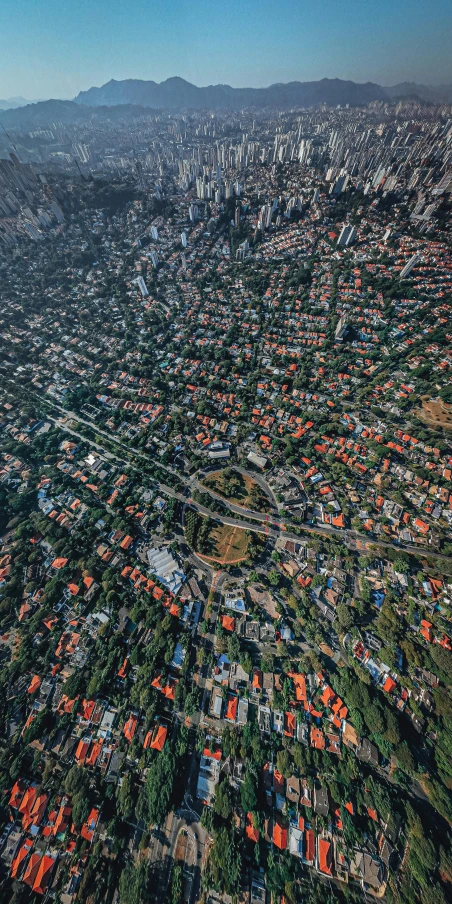 an aerial view of a city with mountains in the background, by Adam Marczyński, pexels, photorealism, top down perspecrive, colombo sri lanka cityscape, dutch angle from space view, detailed photo 8 k