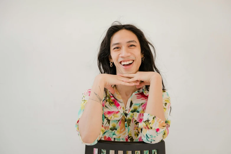 a woman sitting at a table with a keyboard in front of her, an album cover, inspired by Ruth Jên, pexels contest winner, visual art, earing a shirt laughing, in front of white back drop, lei min, holding paintbrushes