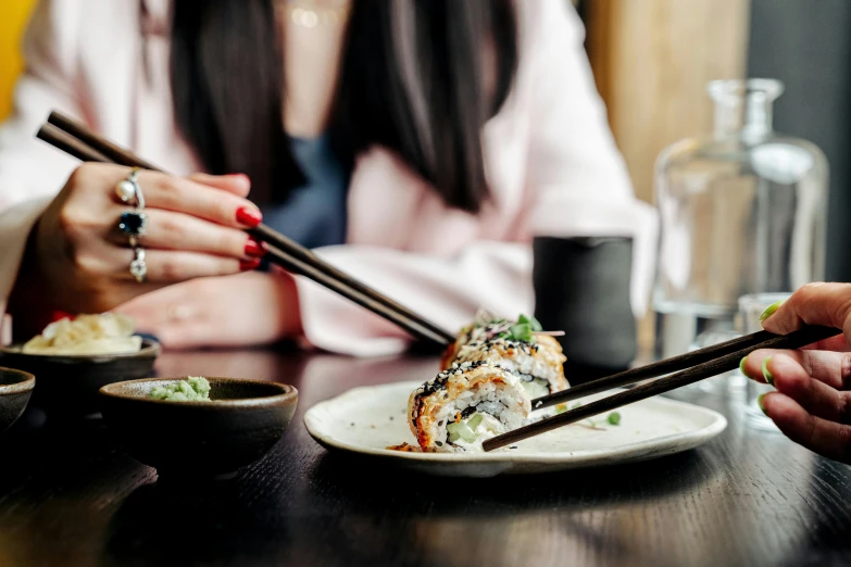 a woman eating sushi with chopsticks at a restaurant, inspired by Maki Haku, trending on unsplash, pale pink and gold kimono, 🦩🪐🐞👩🏻🦳, amanda lilleston, blue