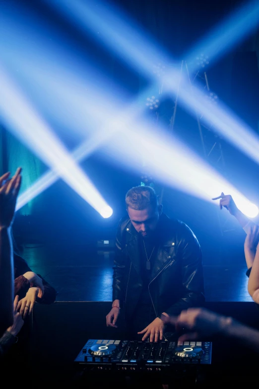 a group of people that are standing in front of a dj, spotlighting, sitting down, ( ( theatrical ) ), holy lights