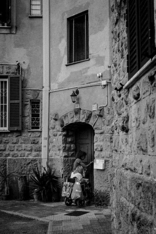 a black and white photo of a woman and a child, by Giuseppe Camuncoli, pexels contest winner, renaissance, french village exterior, about to enter doorframe, medium format. soft light, cannes