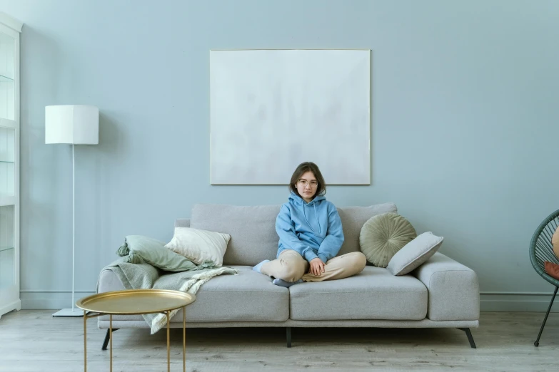 a woman sitting on a couch in a living room, a minimalist painting, inspired by Elsa Bleda, trending on pexels, visual art, pale blue outfit, teenage boy, concerned, in a frame