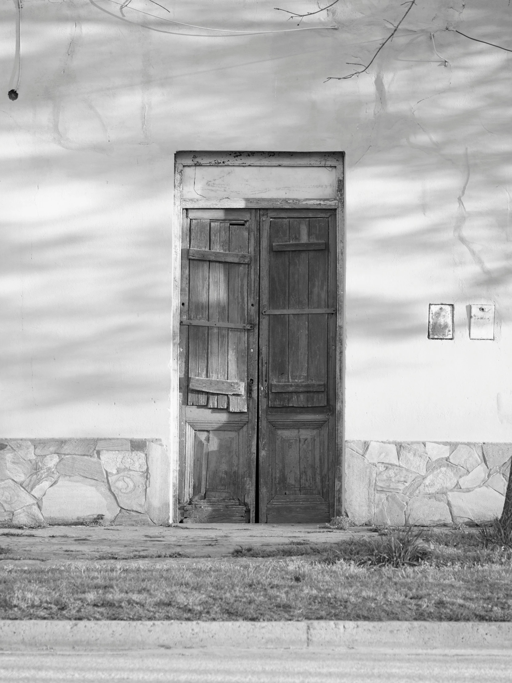 a black and white photo of an old building, a black and white photo, by andrei riabovitchev, wood door, in chuquicamata, 2017, 1970s