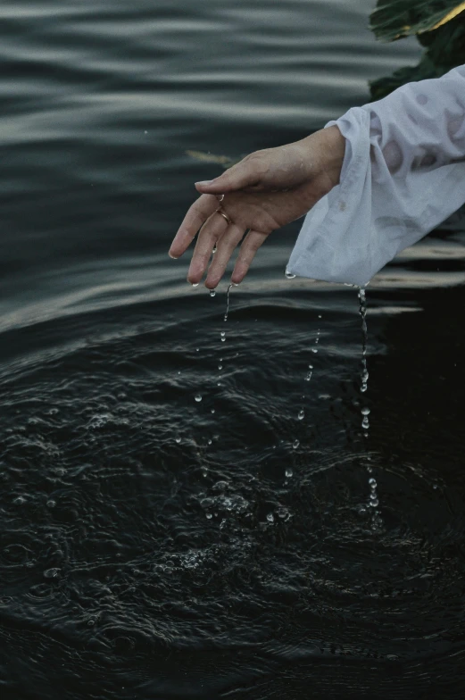 a person in a boat on a body of water, an album cover, inspired by Elsa Bleda, unsplash, renaissance, sleek hands, drops of water, white sleeves, black-water-background