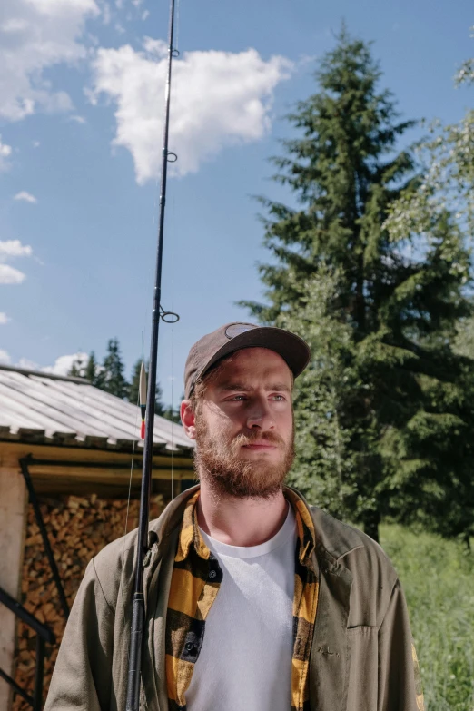 a man standing in front of a cabin holding a fishing pole, a portrait, by Alexander Runciman, unsplash, wide film still, avatar image, zach hill, multiple stories