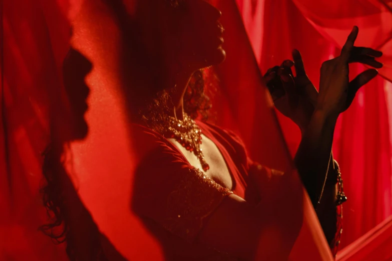 a woman standing in front of a red curtain, inspired by Carrie Mae Weems, pexels contest winner, arabesque, woman holding another woman, veils and jewels, cinematic and dramatic red light, person in foreground