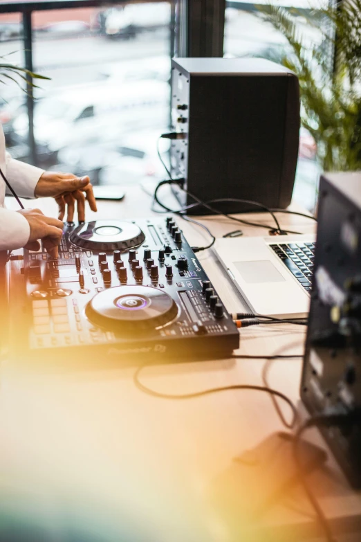 a man sitting at a table in front of a laptop computer, an album cover, trending on unsplash, happening, dj mixer, industrial party, stage speakers, creating a soft