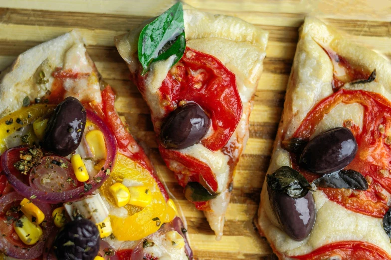 a couple of slices of pizza sitting on top of a cutting board, by Julia Pishtar, olives, thumbnail, multicoloured