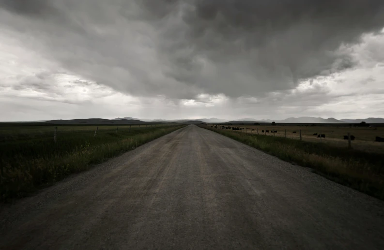 a black and white photo of a dirt road, an album cover, unsplash, realism, todd hido, dark storm clouds, wyoming, color photograph