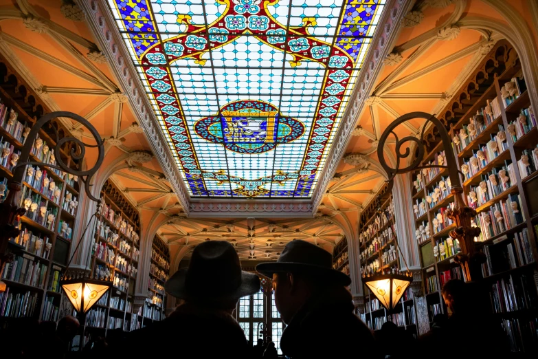a couple of people standing next to each other in a library, a mosaic, pexels contest winner, art nouveau, canopies, drugstore, vaulted ceiling, square