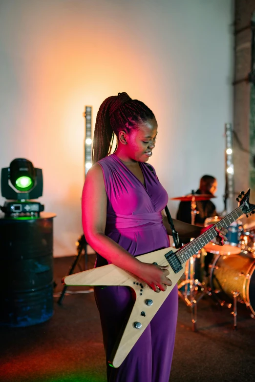 a woman in a purple dress playing a guitar, pexels contest winner, happening, african cyberpunk wizards, performing a music video, on display, epk