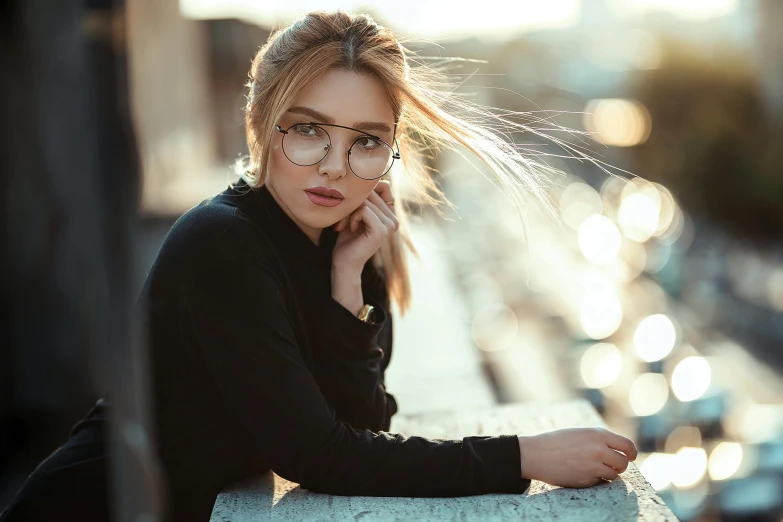 a woman with glasses sitting on a ledge, trending on pexels, anastasia ovchinnikova, square rimmed glasses, perfect face ), evening time