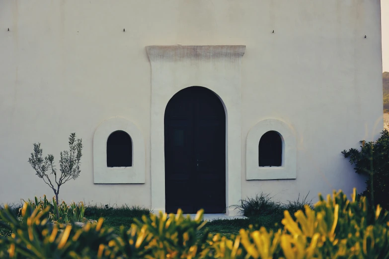 a white building with a clock on top of it, a minimalist painting, pexels contest winner, arched doorway, botanical garden, middle eastern, black house