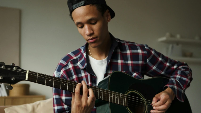 a man playing a guitar in a living room, inspired by Gerard Sekoto, pexels contest winner, realism, male teenager, mixed race, profile pic, thumbnail