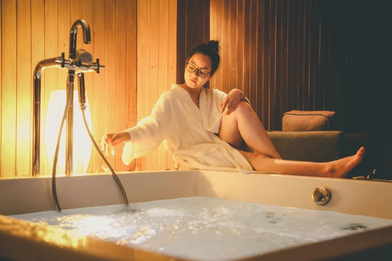 a woman sitting in a bathtub next to a lamp, trending on pexels, hot tub, manuka, sitting in a lounge, profile image