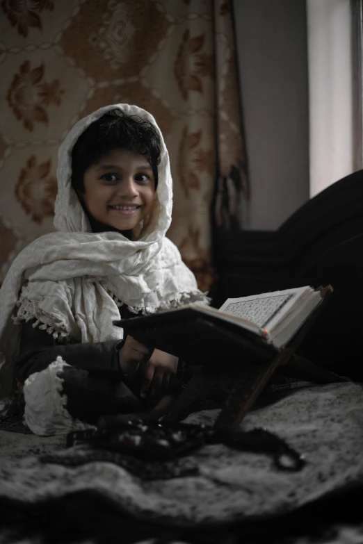 a woman sitting on a bed reading a book, an album cover, inspired by Abdur Rahman Chughtai, pexels contest winner, hurufiyya, little kid, film still from the movie, ornately dressed, pupil