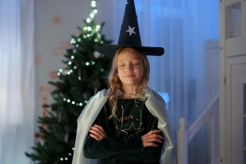 a little girl dressed as a witch standing in front of a christmas tree, pexels, dressed as a wizard, merlin, navy, fairy lights