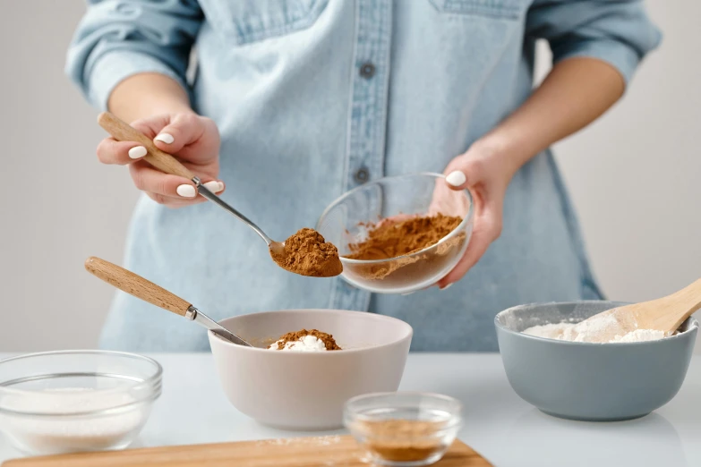 a woman mixing ingredients in a bowl on a table, trending on pexels, cinnamon, avatar image, background image, burnt umber and blue