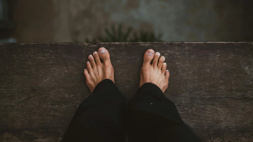 a person standing on top of a wooden bench, by Niko Henrichon, pexels contest winner, exposed toes, black, background image, meditation