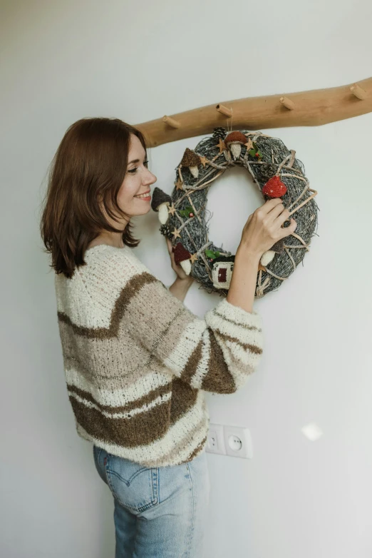 a woman hanging a wreath on a wall, wearing casual sweater, great quality ), trending photo, profile image