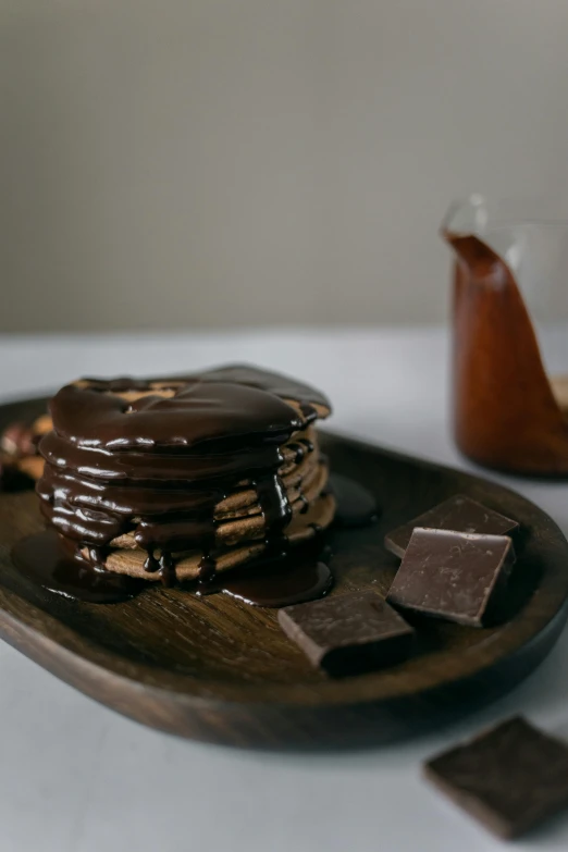 a stack of pancakes sitting on top of a wooden plate, a still life, unsplash, smothered in melted chocolate, gif