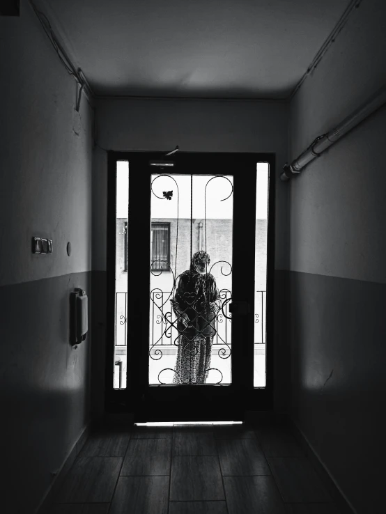 a black and white photo of a person standing in a doorway, by Lucia Peka, unsplash, tehran, an elderly, captured on iphone, apartment