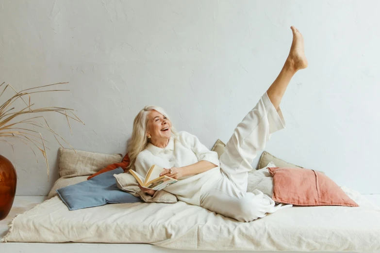 a woman laying on a bed reading a book, pexels contest winner, old lady screaming and laughing, full body sarcastic pose, high soles, white haired