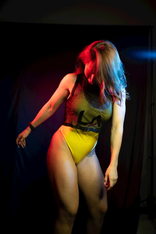 a woman in a yellow bathing suit posing for a picture, an album cover, unsplash, dance music show, backlighted, indoor picture, bodypaint