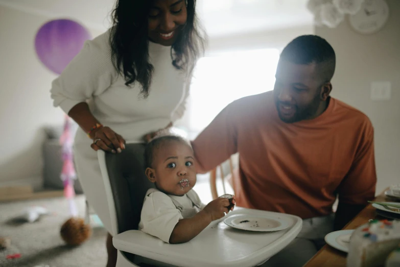 a man and woman feeding a baby in a high chair, pexels contest winner, dark-skinned, caring fatherly wide forehead, husband wife and son, 1 2 9 7