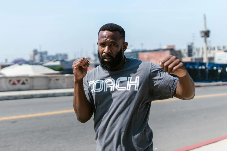 a man standing on the side of a road, wearing a tee shirt and combats, fist training, zochi, profile image