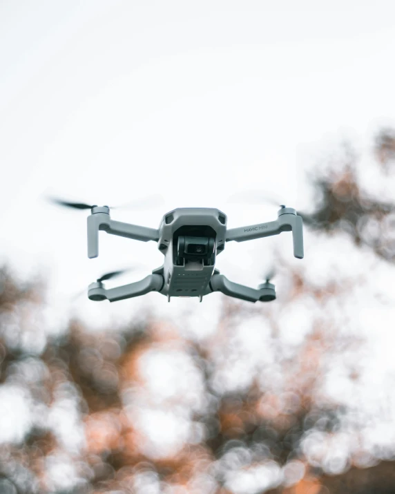 a white drone flying in the air with trees in the background, pexels contest winner, gif, grey, toys, religious