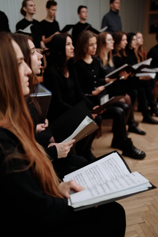 a group of people sitting on top of a wooden floor, choir, woman in black robes, half image, russian academic